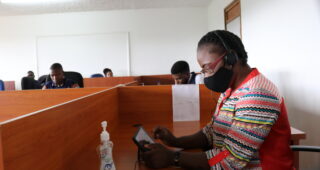 Nurse Kettie Juma at work in a call center, socially distanced and wearing a face mask