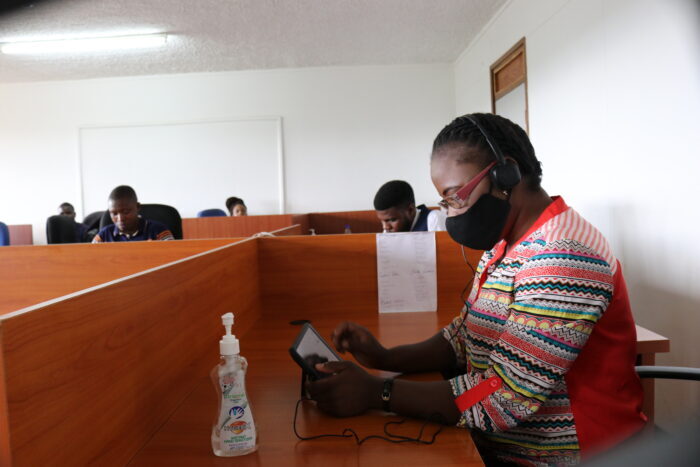 Nurse Kettie Juma at work in a call center, socially distanced and wearing a face mask