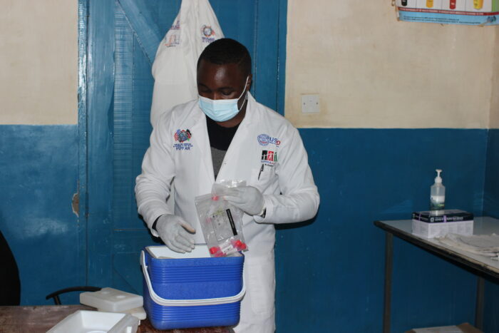 Ndeiya health care laboratory staff Anthony Mburia packages positive COVID-19 samples into a cooler box for transport for genomic sequencing.  