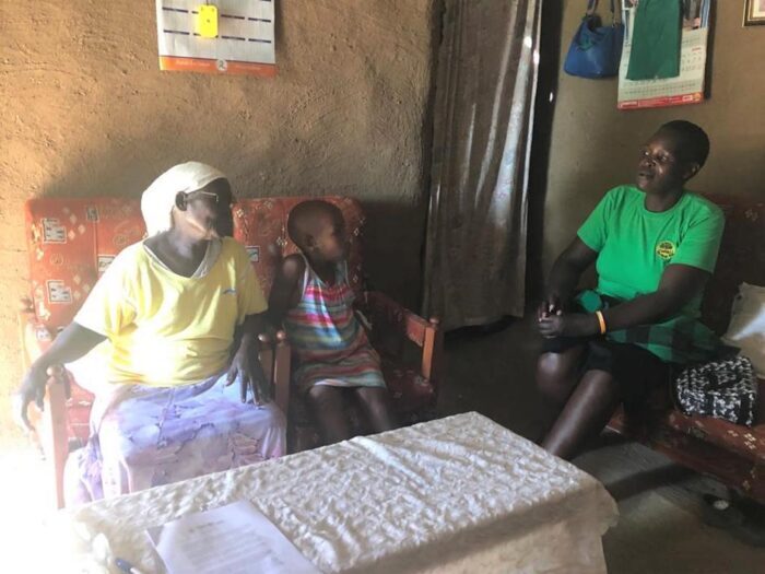 Grandmother and child meeting with OVC worker in home.