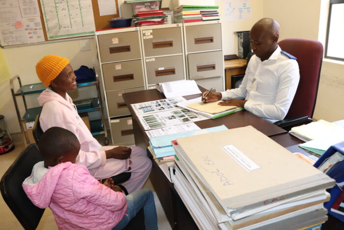 Caregiver and child meet with healthcare worker in a clinic office in Lesotho